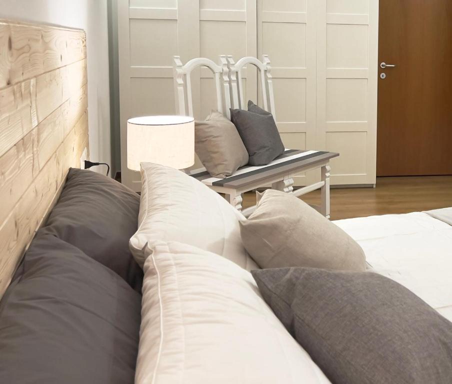 een slaapkamer met een bed en een stoel met kussens bij Appartamento nel Borgo in Rovereto