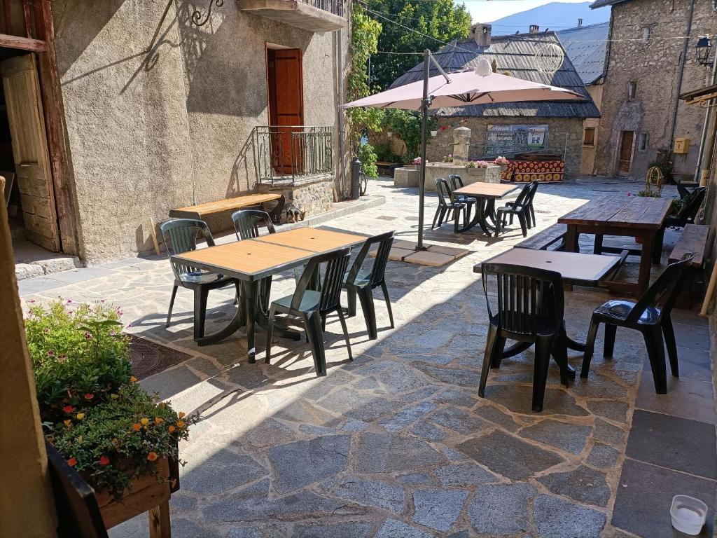 a patio with tables and chairs on a stone floor at Auberge l'écureuil in Châteauneuf-dʼEntraunes