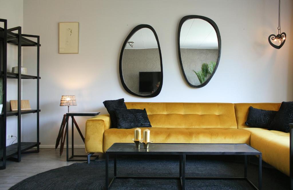 a living room with a yellow couch and two mirrors at HOLTINGERHUYS Uffelte- Giethoorn! Optie Wellness!!! in Uffelte