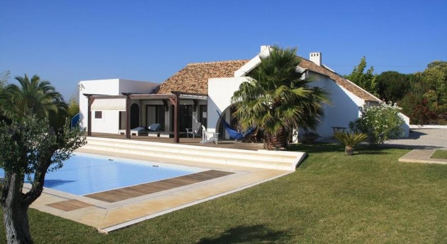 a villa with a swimming pool in front of a house at Villa Oasis Azul - beautiful villa with heated private pool short walk to all amenities in Sesimbra