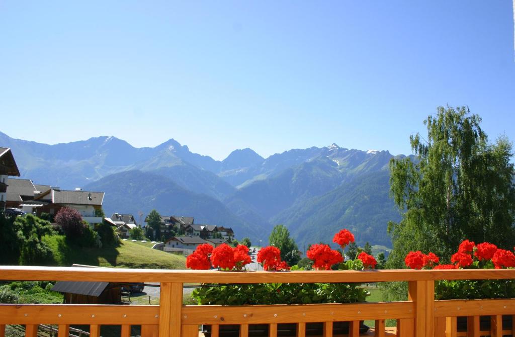 einen Balkon mit roten Blumen und Bergblick in der Unterkunft Lili's Appartements in Fiss