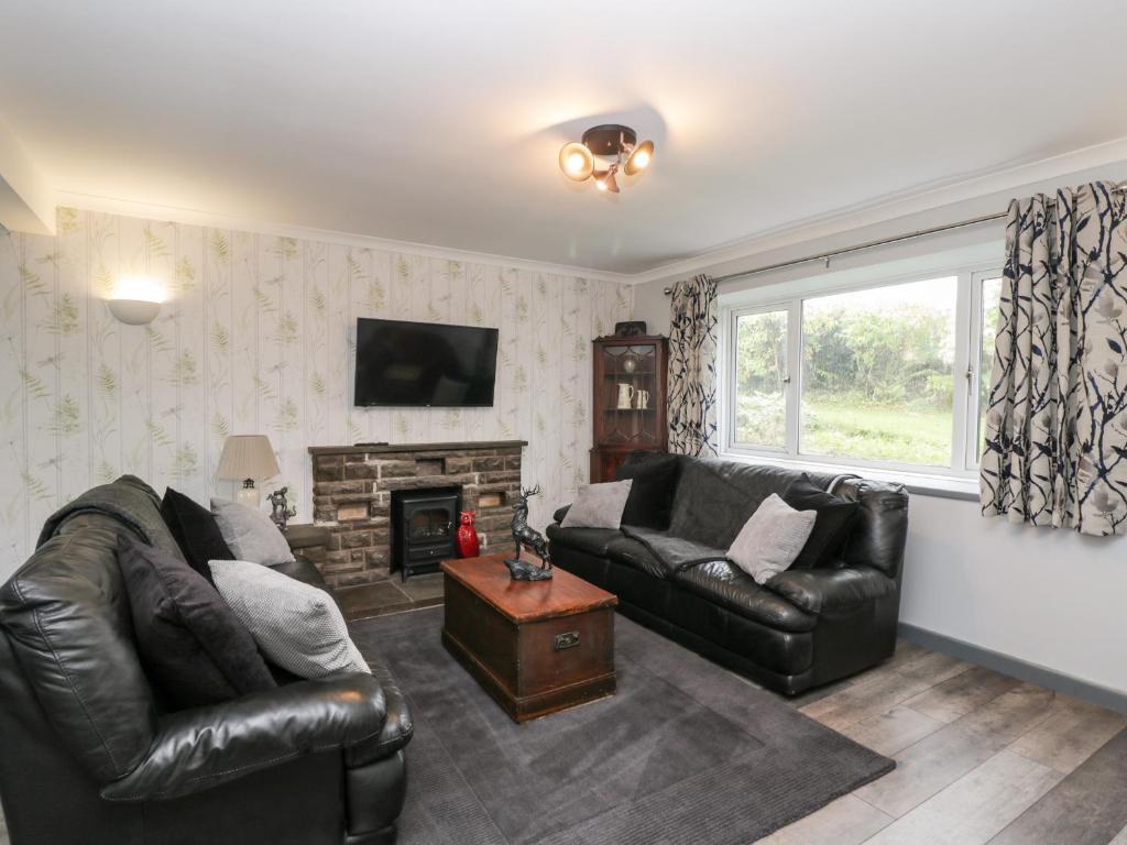 a living room with two leather couches and a fireplace at Pool House in Monmouth