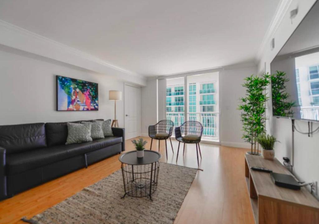 a living room with a black couch and chairs at 2BD Condo At Brickell With Bay View in Miami