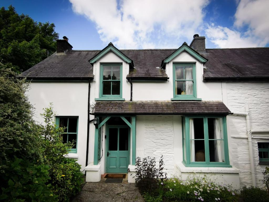 Casa blanca con puertas y ventanas verdes en Wellstone Cottages - Jasmine en Llanfyrnach