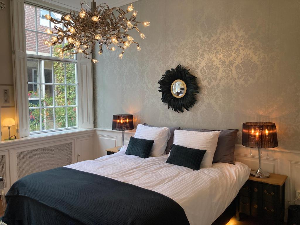 a bedroom with a large bed with two lamps and a chandelier at GuesthouseOne in Haarlem