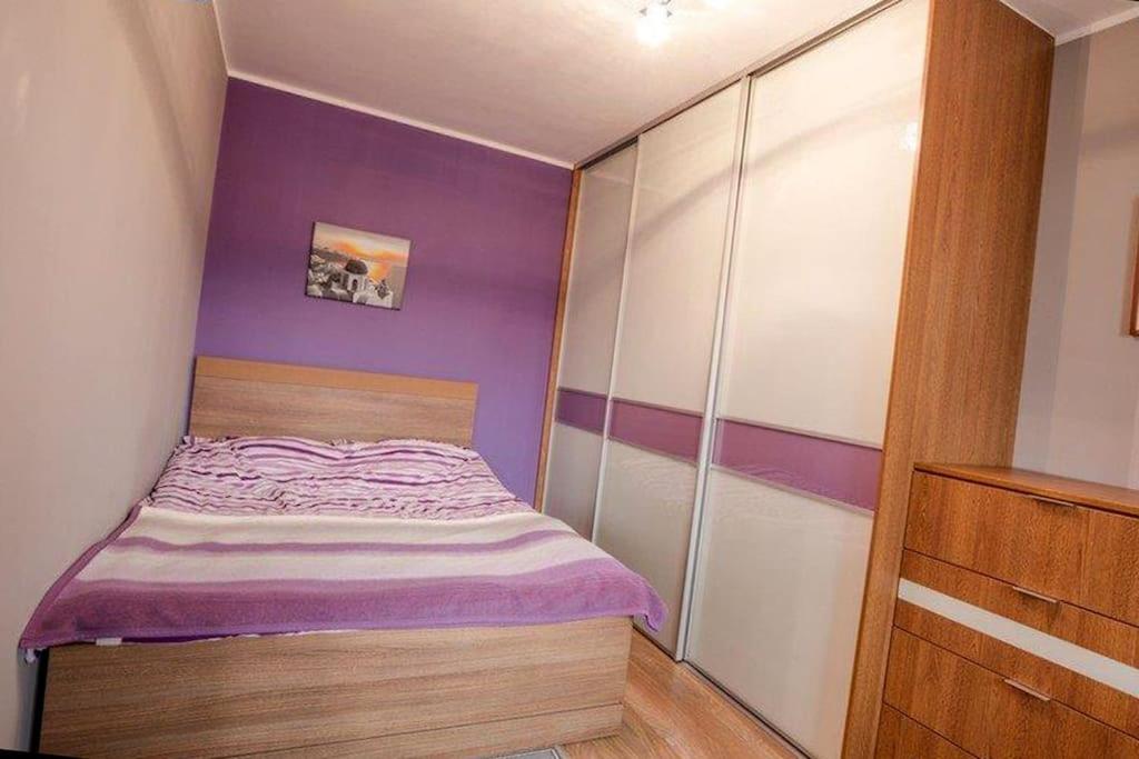 a small bedroom with purple and white walls and a bed at Gdansk Old Town 2 room Apartment in Gdańsk