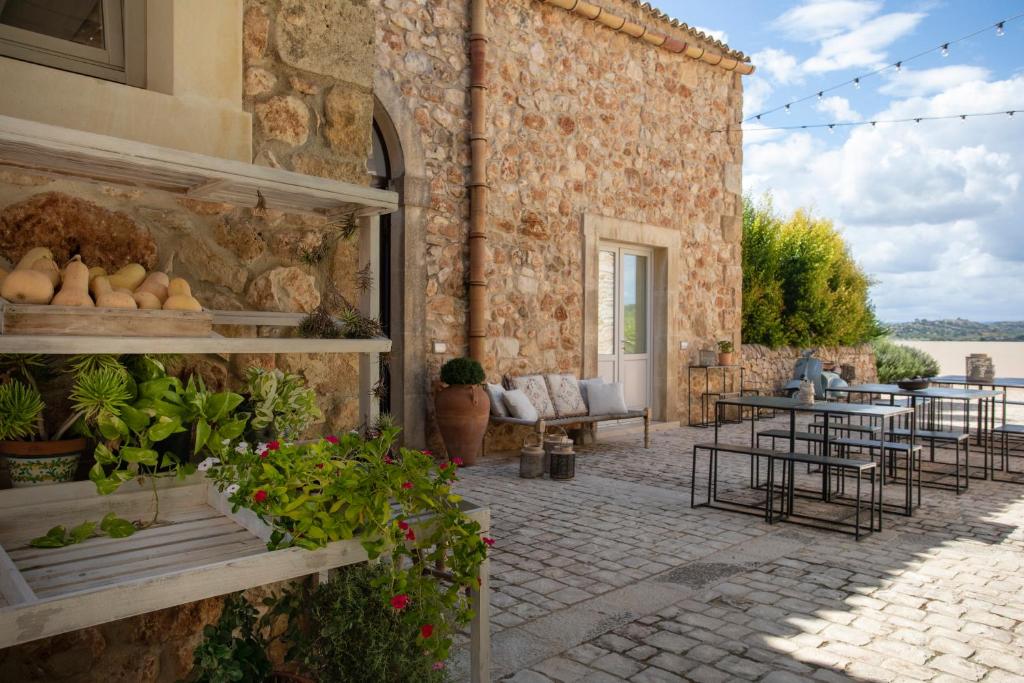 un edificio de piedra con un patio con mesas y sillas en I Carusi Relais, en Noto
