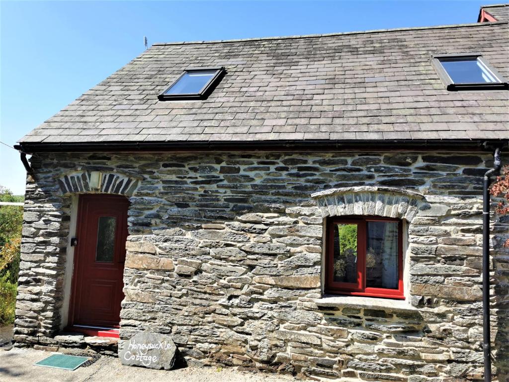 a stone building with a red door and windows at Wellstone Cottages - Honeysuckle in Llanfyrnach