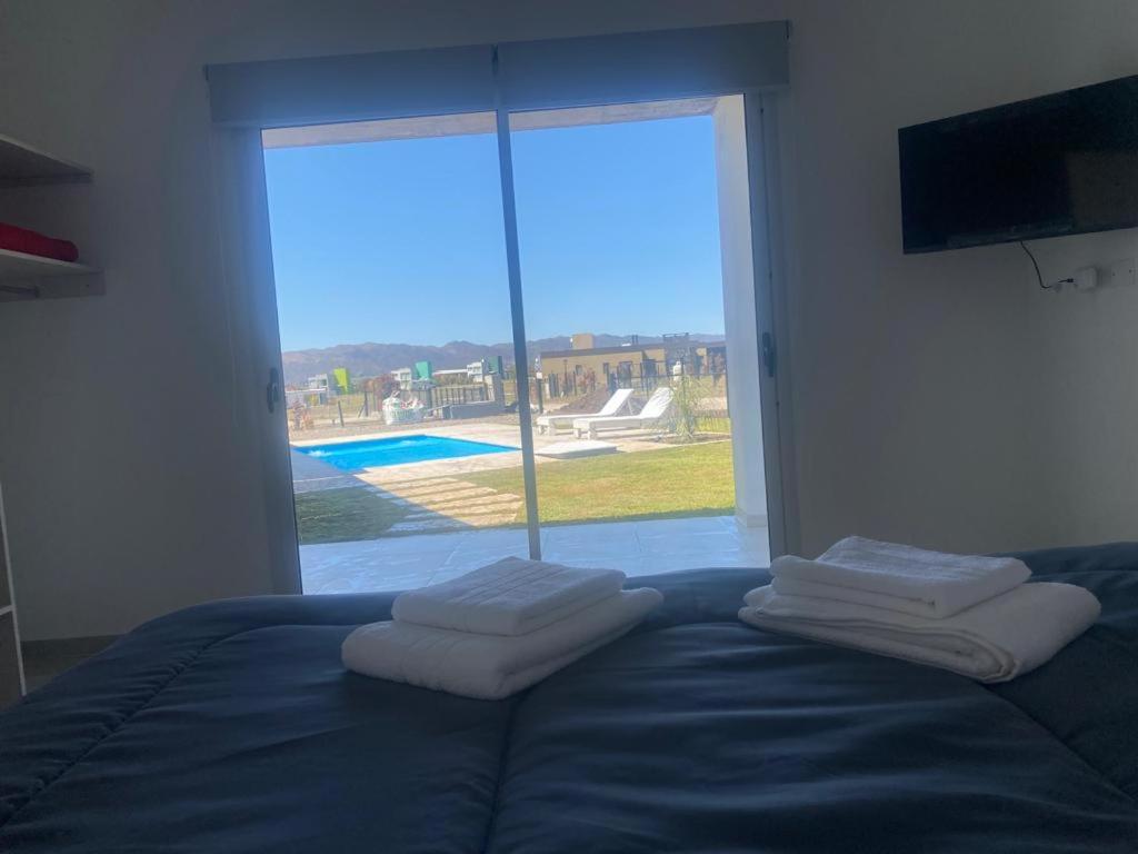 a bedroom with a bed and a large window with towels at AIRES DEL LAGO, Los Molinos 2 in Potrero de Garay