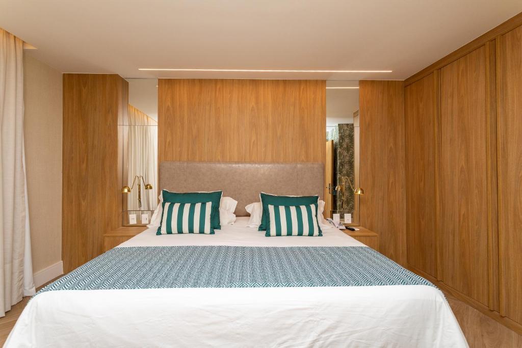 a bedroom with a large bed with green and white pillows at Mar Ipanema Hotel in Rio de Janeiro