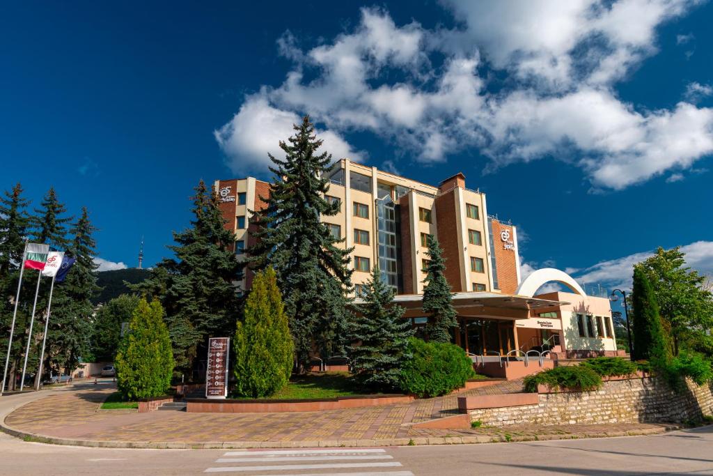 un gran edificio con árboles delante de él en Хотел "Скалите", Skalite Hotel en Belogradchik