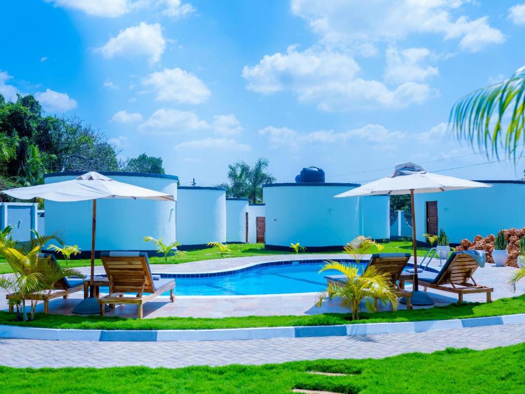 a swimming pool with two chairs and umbrellas at homeland bro in Dar es Salaam