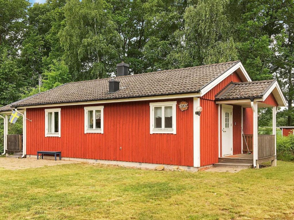 uma casa vermelha com um banco num quintal em Holiday home SÖLVESBORG XVI em Sölvesborg