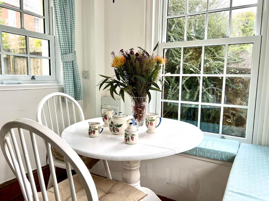 Una mesa blanca con un jarrón de flores. en Cosy 2 bed cottage on Dartmoor , Near Ivybridge en Plymouth