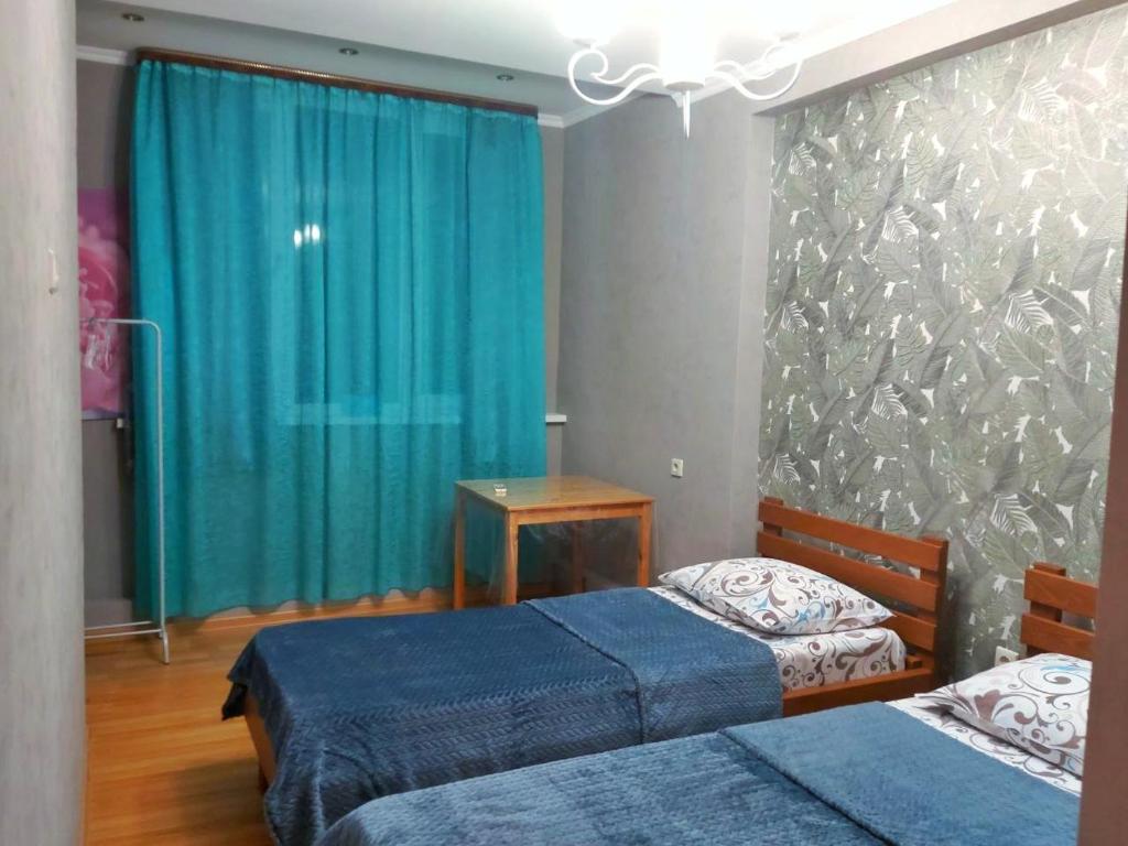 a bedroom with two beds and a blue curtain at Двухкомнатная квартира в Пицунде in Pizunda