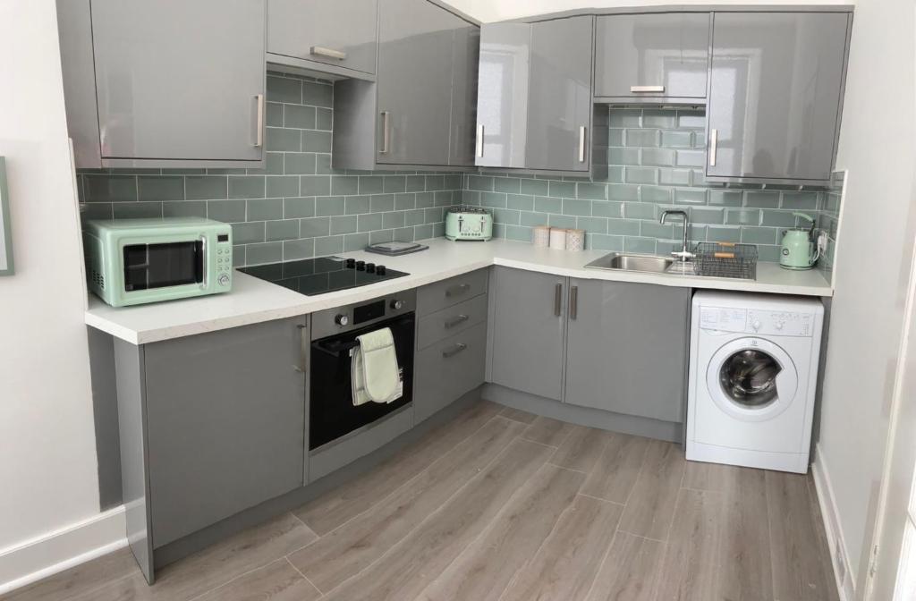 a kitchen with a washing machine and a microwave at The Princess Flat, Helensburgh. in Helensburgh