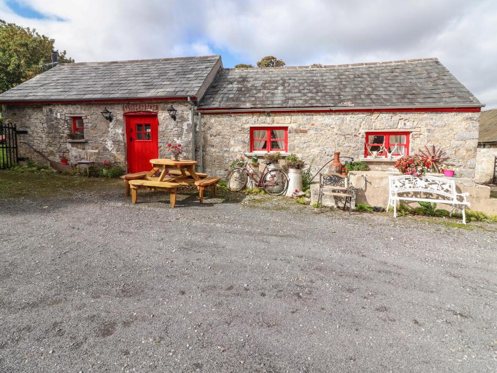 a stone house with a picnic table and a red door at The Dairy in Clonmel