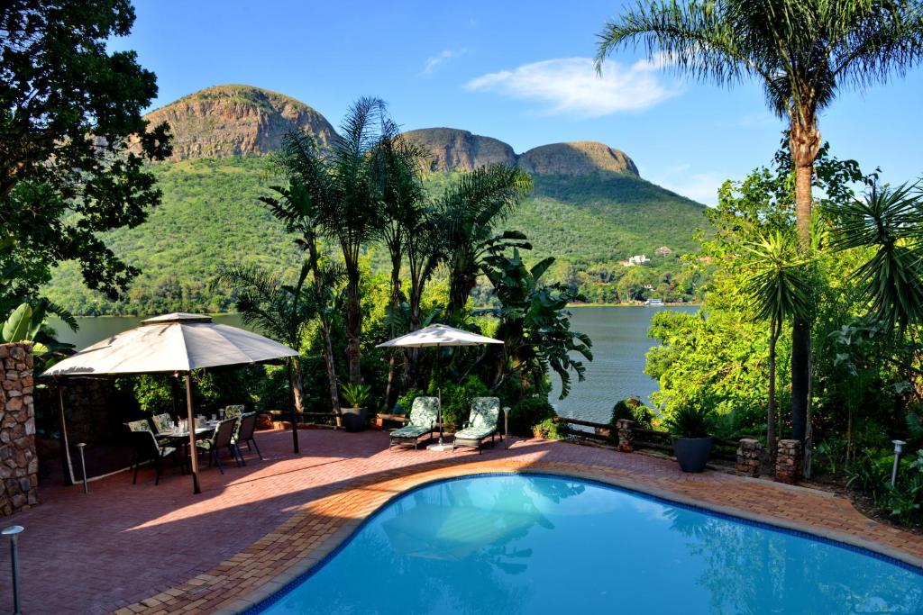 una piscina con montañas en el fondo en The Shore House, en Hartbeespoort