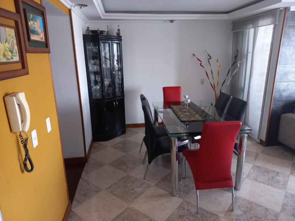 APARTA-HOTEL BADEN في بوغوتا: غرفة طعام مع طاولة وكراسي حمراء