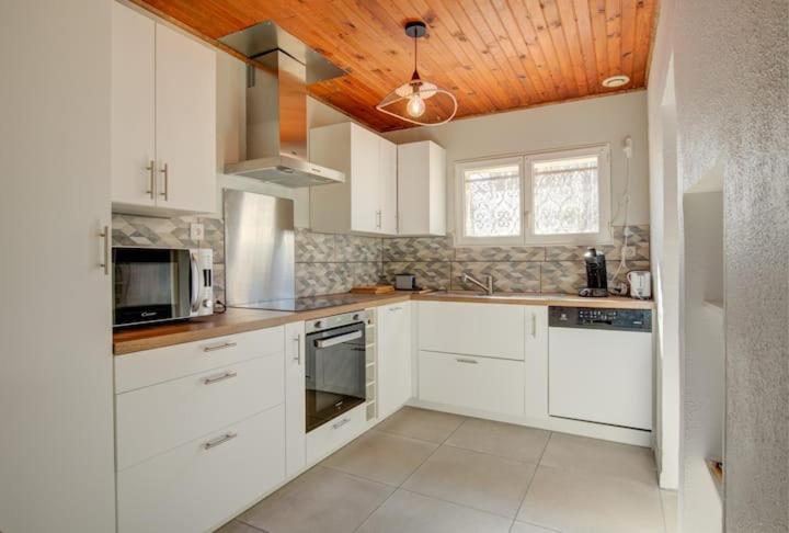 une cuisine avec des armoires blanches et un plafond en bois dans l'établissement Maison 8 couchages Arès, à Arès