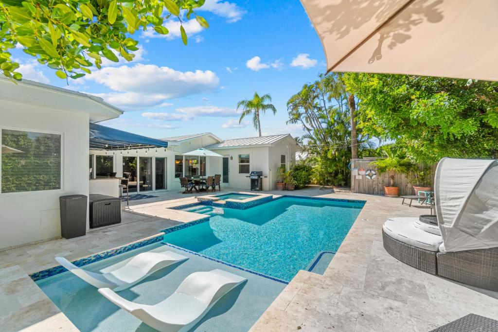 a swimming pool in the backyard of a house at Seaside Elegance - 4B-4B - 3 Master Suites, Heated Pool and Spa, Tanning Ledge, Golden Tee Arcade, Outdoor Bar with 65 Inch TV, BBQ, Walk to Beach! Sleeps 10 in West Palm Beach