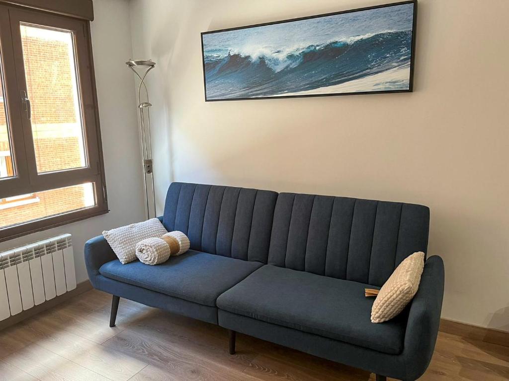 un sofá azul en una habitación con una pintura en la pared en Apartamento Barrio de la Arena, en Gijón