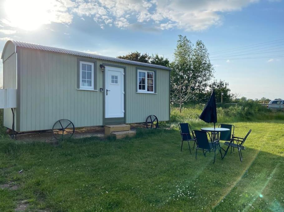 uma pequena casa com uma mesa e cadeiras na relva em Beautiful 1 Bed Shepherd Hut in Warwickshire em Warwick