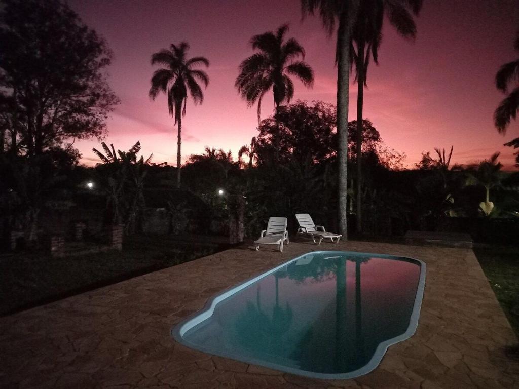una piscina con due sedie e un tramonto di Cabana na Serra do Itaqueri com fogão a lenha e churrasqueira a Itirapina