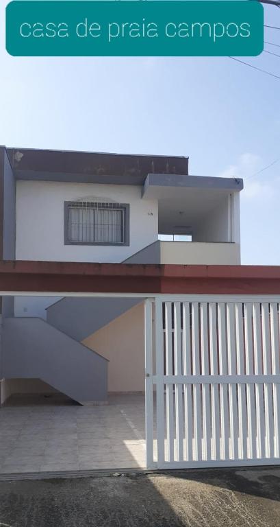 a building with a white railing and a fence at casa de praia campos in Itanhaém