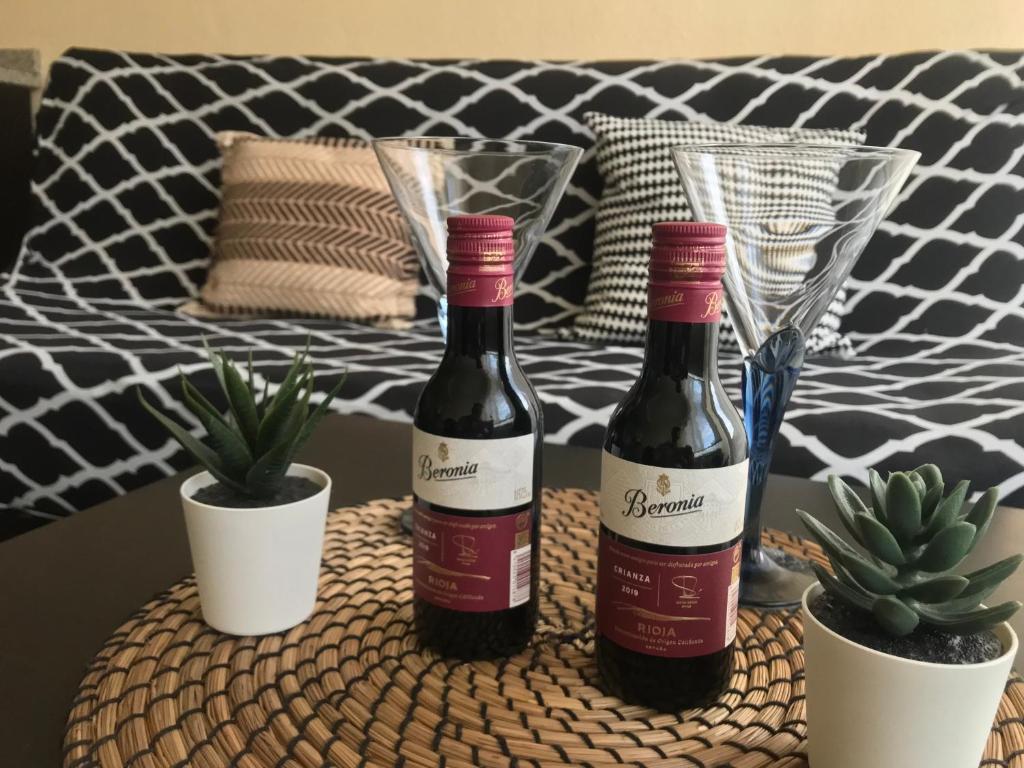 Apartamento Haro Wine Experience في هارو: زجاجتان من النبيذ تقعان على طاولة مع النباتات