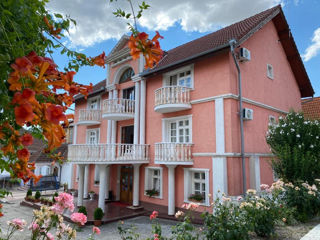 a large pink building with balconies and flowers at Pensiunea Ana in Baile Felix