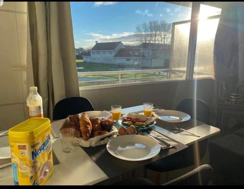 une table avec une assiette de nourriture et une fenêtre dans l'établissement Un bol d'air à De Haan - Mer du Nord, au Coq