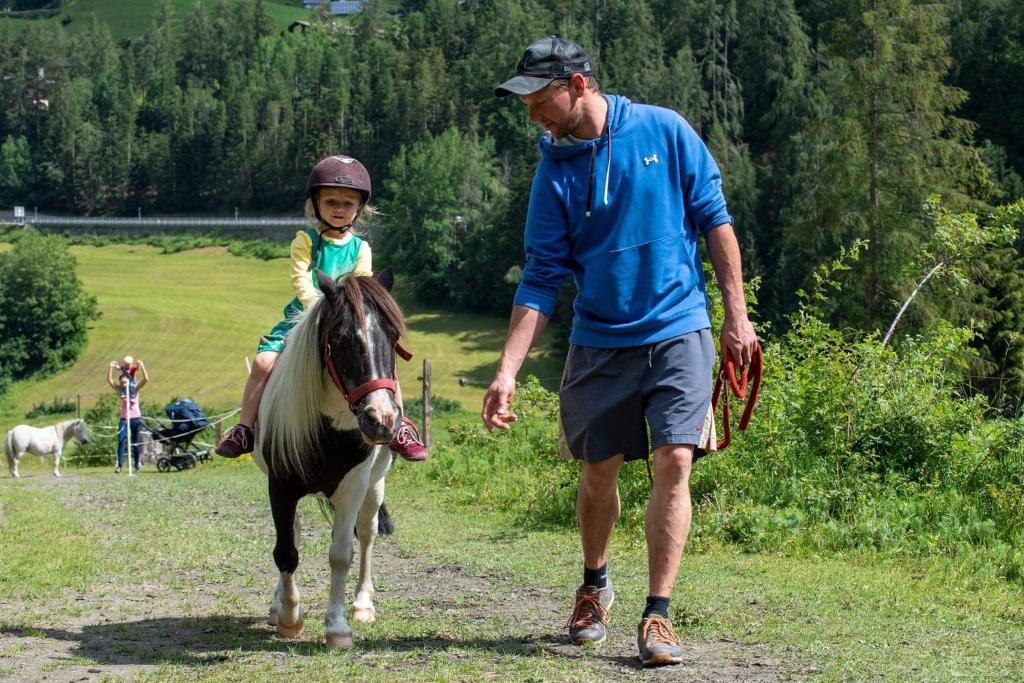 a man and a young girl riding a horse with a man at Bauernhof Stempf in Heiligenblut