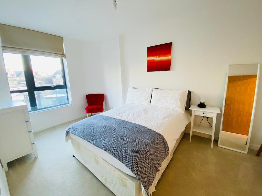 a white bedroom with a bed and a red chair at Spacious two Bedroom Apartment in Balham in London