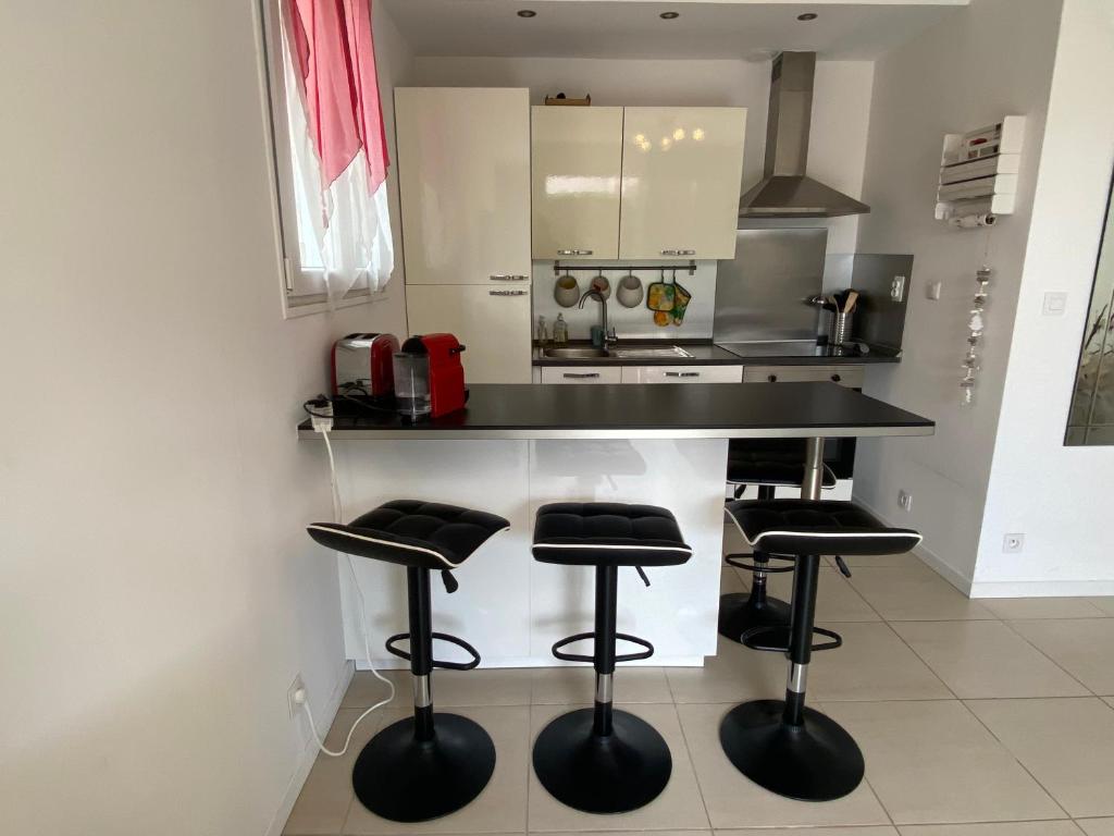 a kitchen with a black counter and stools in it at Les Lones avec jardin in Six-Fours-les-Plages