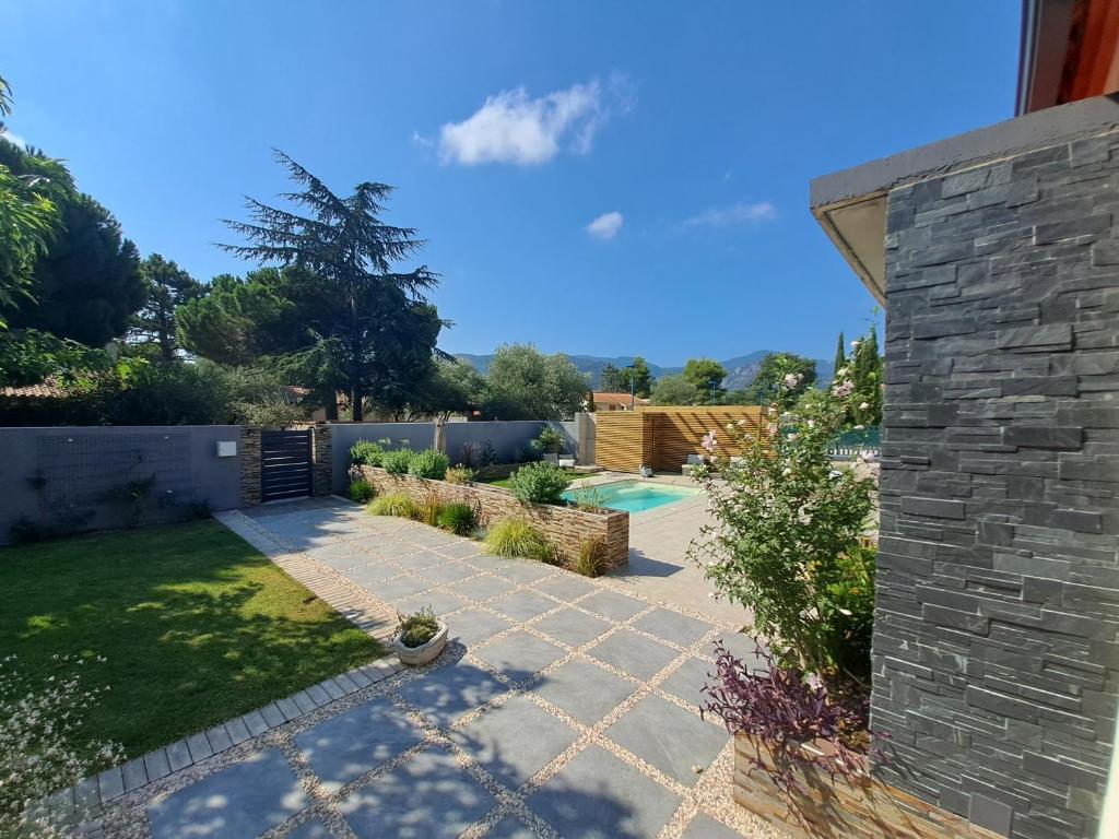 einen Garten mit einer Terrasse und einem Pool in der Unterkunft Belle villa avec piscine vue montagne à 10 mn de la mer à Argeles in Argelès-sur-Mer