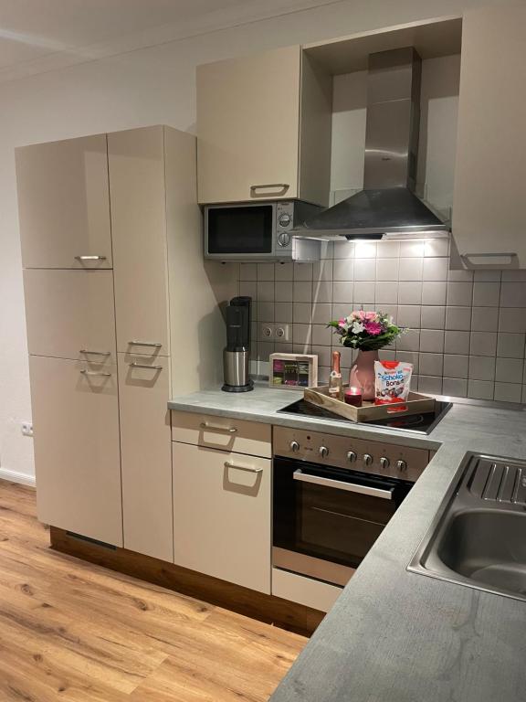 a kitchen with white cabinets and a stove and a sink at Ferienwohnung Ostfriesenherz Emden in Emden