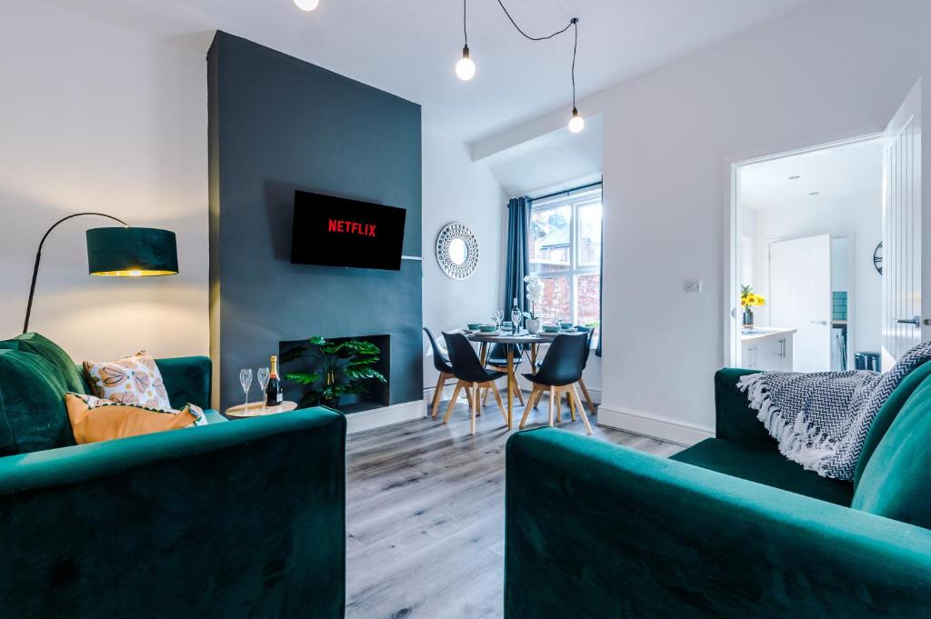 una sala de estar con 2 sofás verdes y una mesa. en Spacious 4-bed house in Crewe by 53 Degrees Property, ideal for Business & Contractors - Sleeps 7, en Crewe