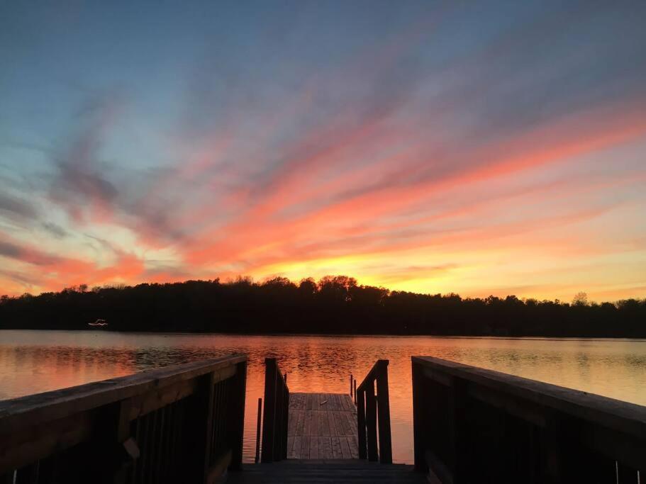 a sunset over a body of water with a dock at Bespoke Lake Cottage in New Minas