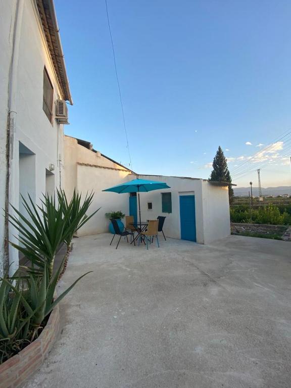 eine Terrasse mit einem Tisch und einem blauen Sonnenschirm in der Unterkunft CASA PAULA in Murcia