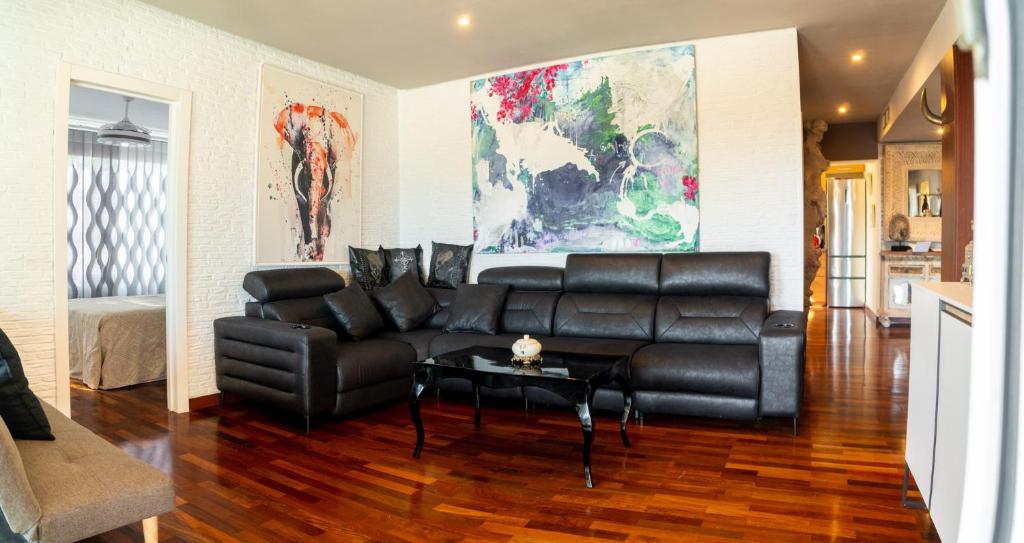 a living room with a black leather couch and a table at Luxury apartamento en río real in Marbella