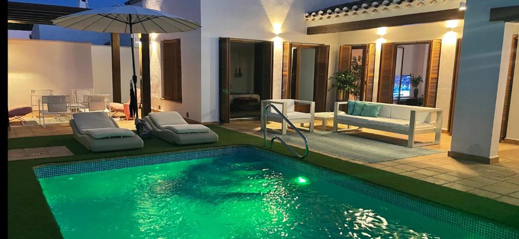 una piscina con sillas y una sombrilla junto a una casa en Villa para disfrutar en el Valle Golf Resort, en Murcia