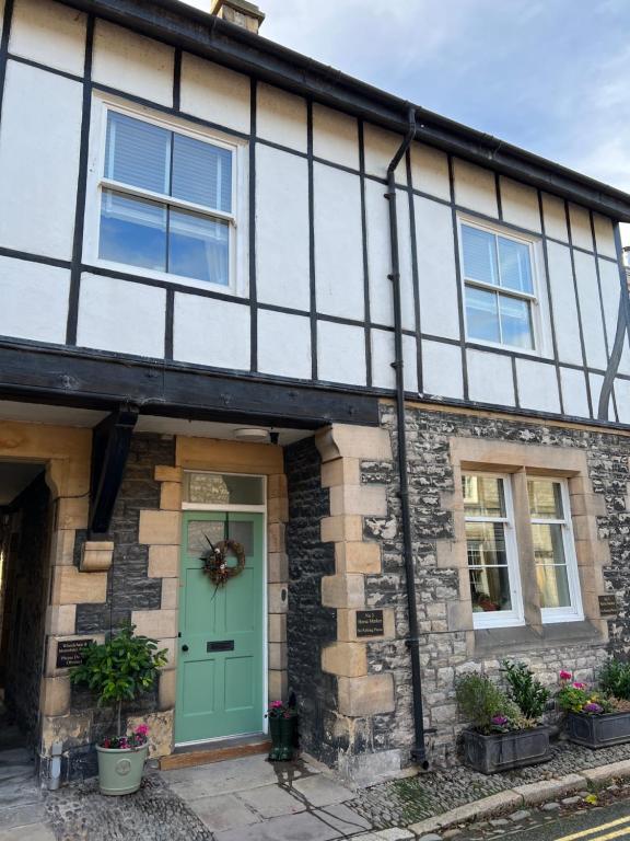 a stone house with a green door and windows at Horse Market Cottage Kirkby Lonsdale in Kirkby Lonsdale