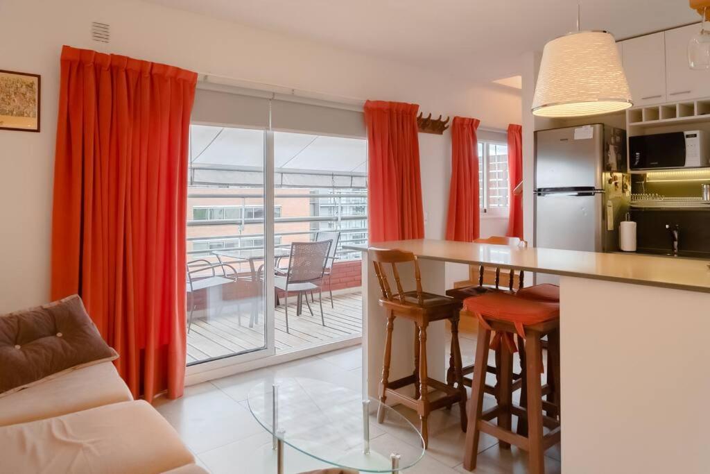 a kitchen with red curtains and a table with chairs at Puerto Madero a metros del Faena in Buenos Aires
