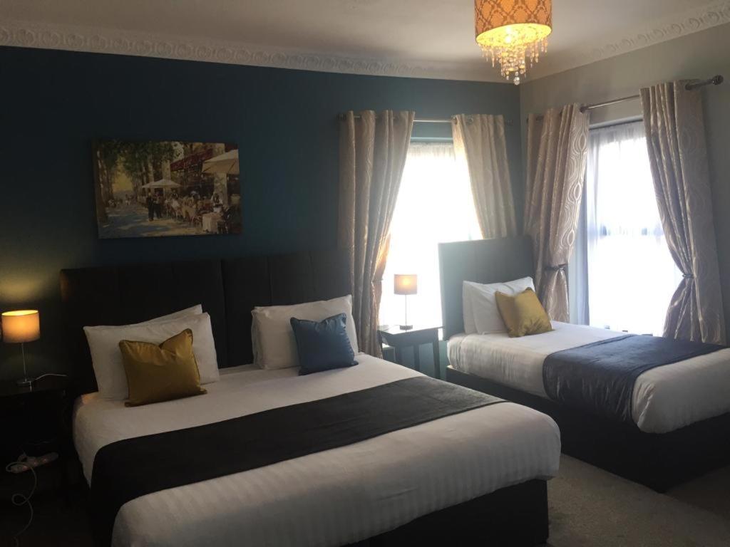 a hotel room with two beds and a chandelier at The Rooms at The Spout in Kilcullen