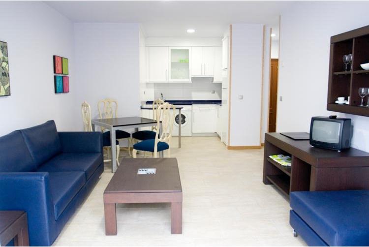 a living room with a blue couch and a table at Apartamentos Turisticos Noray in Argoños