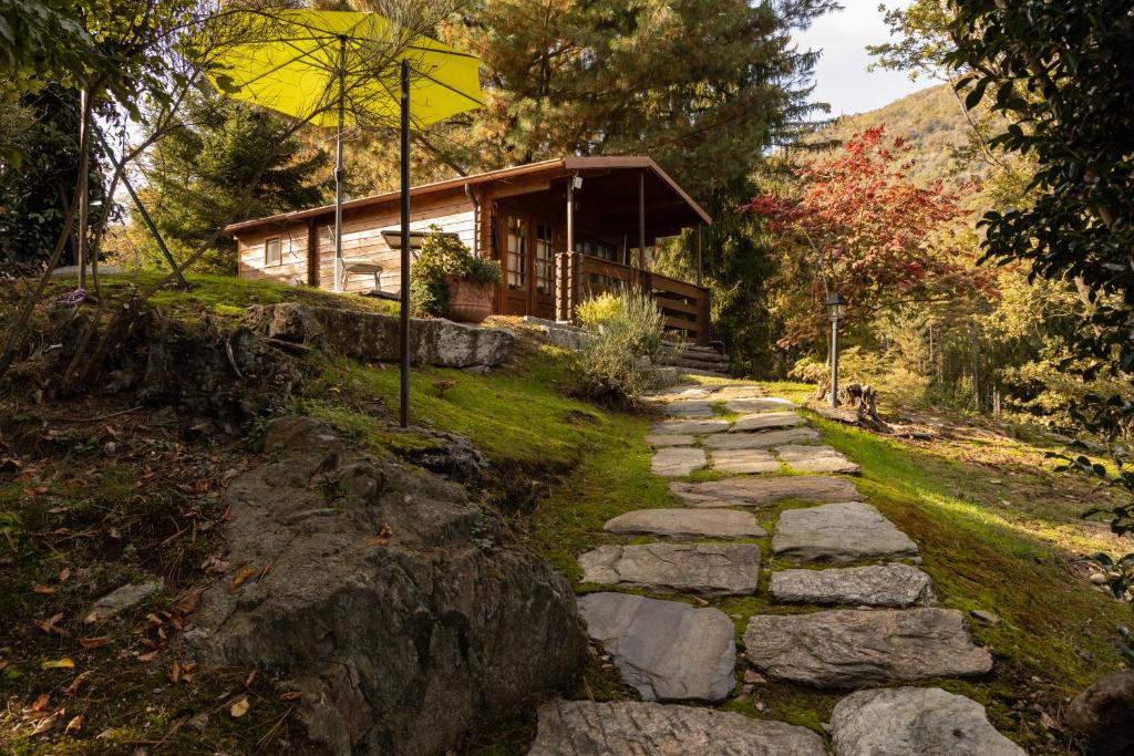 un sentiero in pietra di fronte a una baita di tronchi di Eco-Resort Parco Botanico Fiorlago a Mergozzo