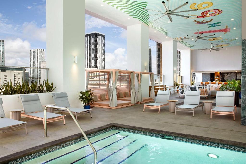 eine Dachterrasse mit einem Pool, Stühlen und einer Uhr in der Unterkunft YOTEL Miami in Miami