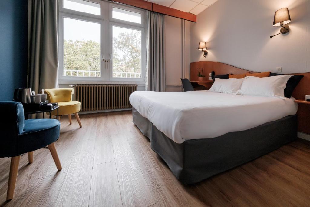 ein Hotelzimmer mit einem großen Bett und einem Stuhl in der Unterkunft Hôtel du Parc in Thionville