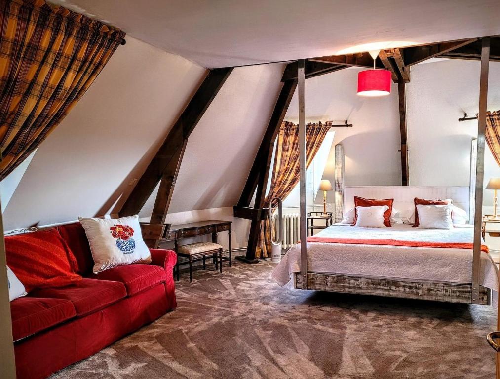 1 dormitorio con 1 cama y 1 sofá rojo en La Coulee Verte en Saint-Aubin-de-Luigné